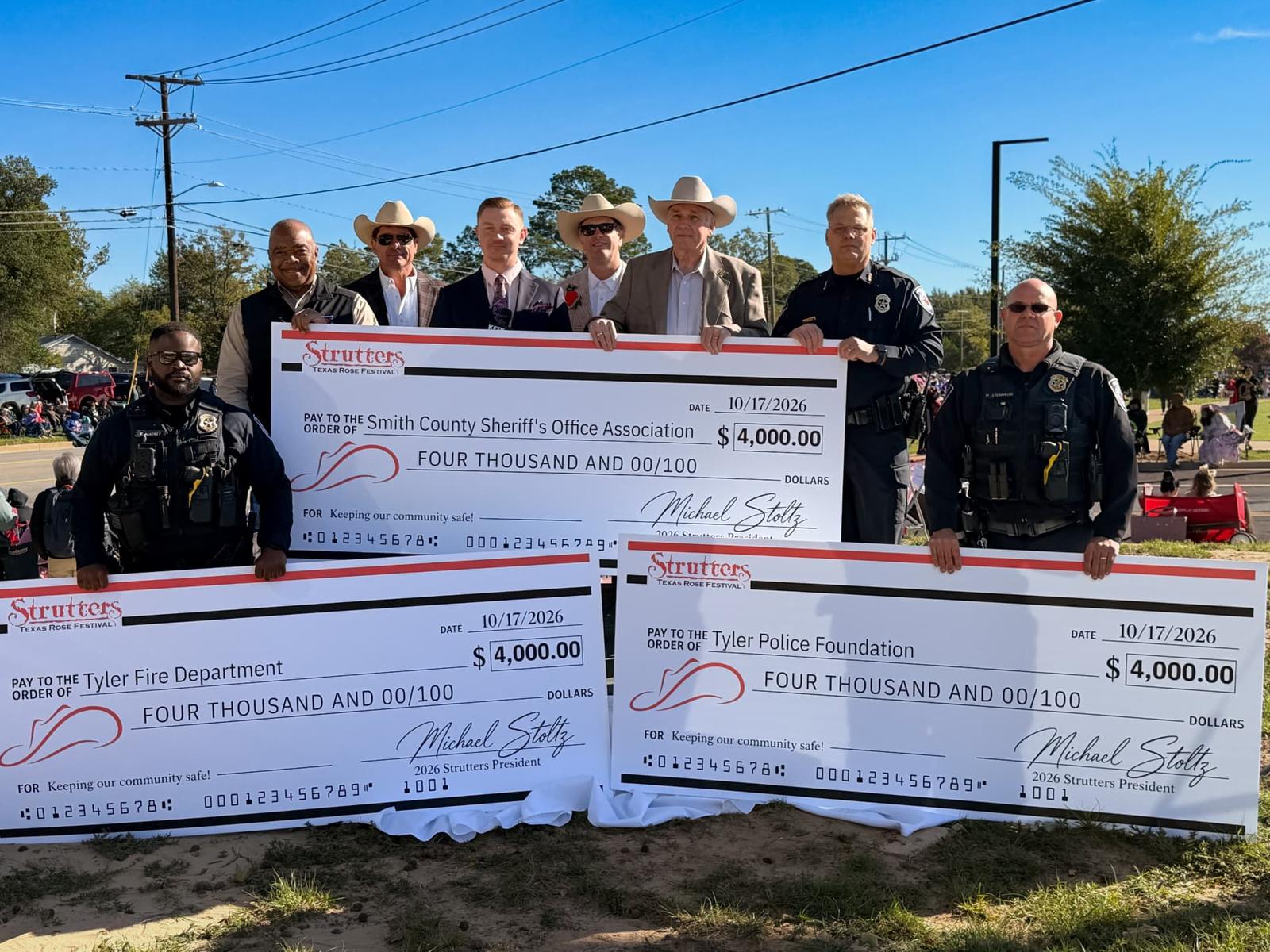 Strutters and Tyler-area first responders holding three $4,000 checks for the Tyler Police Foundation, Tyler Fire Department, and Smith County Sheriff's Office Association at the 2026 Texas Rose Festival Parade